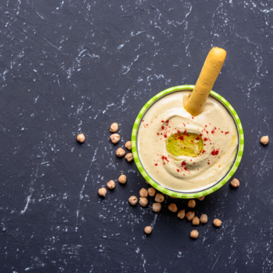 carrot breadsticks with a ball of humus on a marble background